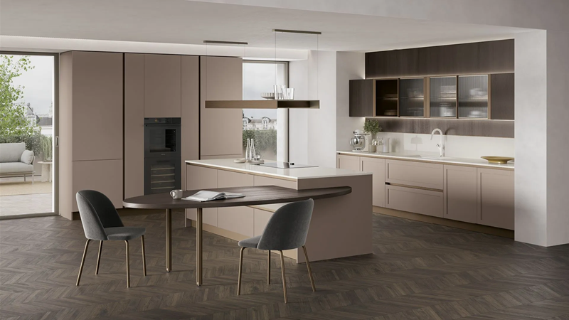 Cucina tortora con isola, cappa sospesa, tavolo ovale in legno scuro, sedie grigie e parquet a spina di pesce